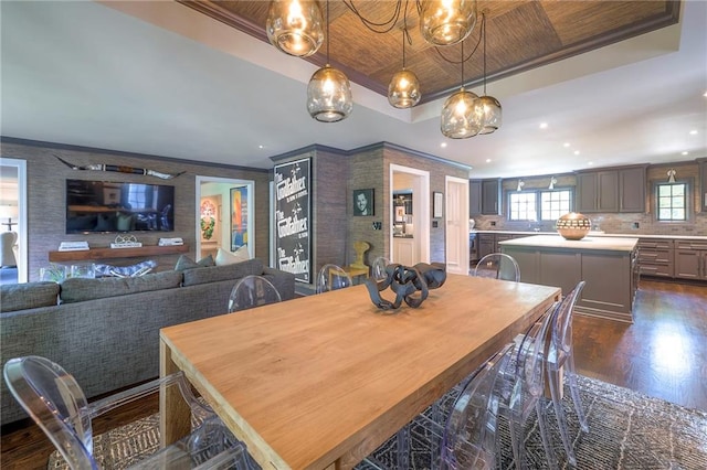 dining space with dark wood-type flooring, ornamental molding, a tray ceiling, and recessed lighting