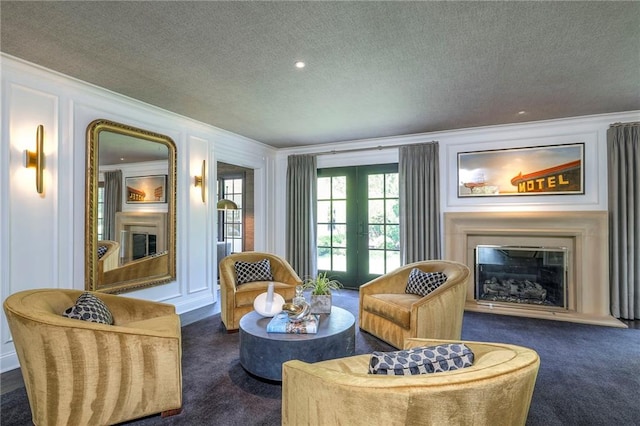 sitting room with a large fireplace, ornamental molding, dark carpet, and a textured ceiling