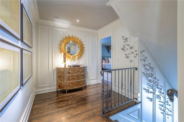 hallway with ornamental molding, dark wood finished floors, and a decorative wall