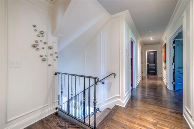corridor with baseboards, an upstairs landing, dark wood-type flooring, and a decorative wall