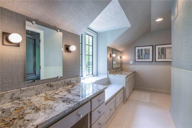 bathroom with vanity, wainscoting, tile patterned floors, and lofted ceiling