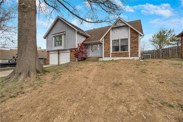 view of front of home with dirt driveway, a garage, fence, and brick siding