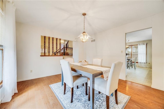 dining area with visible vents, baseboards, an inviting chandelier, stairs, and light wood-style flooring