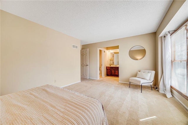 bedroom featuring visible vents, light colored carpet, baseboards, and ensuite bathroom