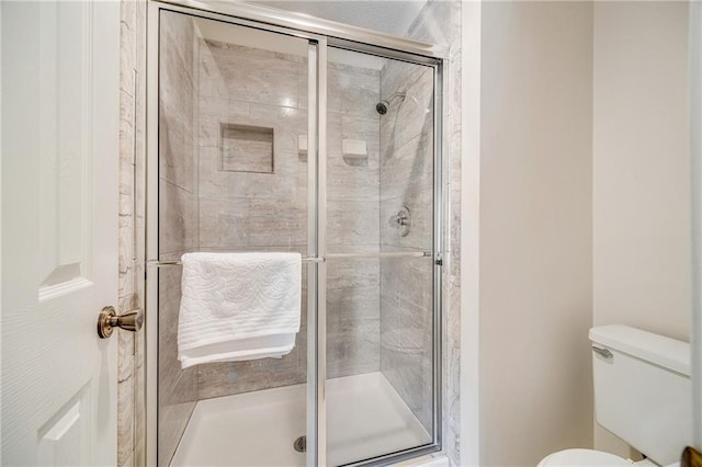 bathroom featuring toilet and a stall shower