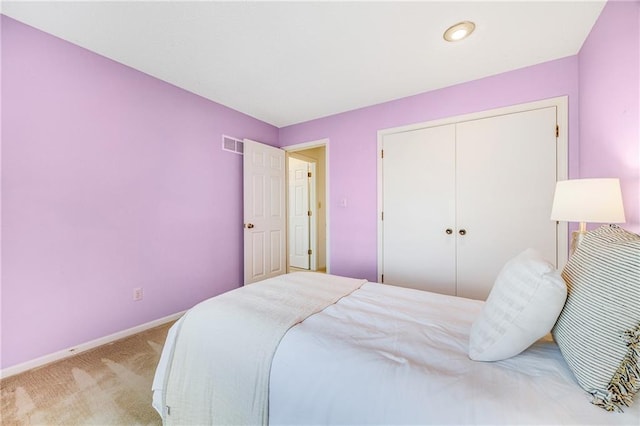 bedroom with a closet, light colored carpet, baseboards, and visible vents