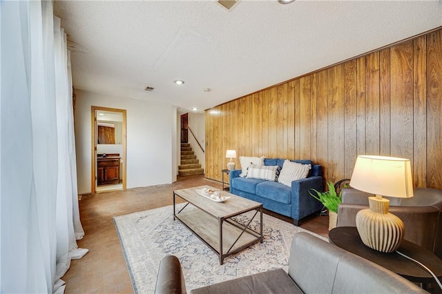 living room featuring wood walls, visible vents, and stairway