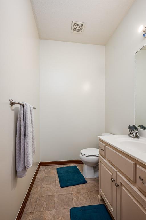 1210 Barnett Ave, Kansas City, KS 66102 - bathroom with vanity, toilet, baseboards, and stone finish floors