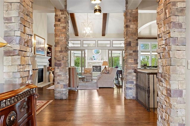 interior space with wood-type flooring, ornate columns, beamed ceiling, and a fireplace
