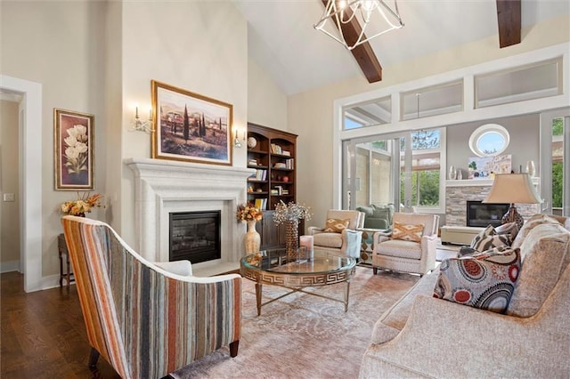 living area with an inviting chandelier, wood finished floors, high vaulted ceiling, baseboards, and a glass covered fireplace