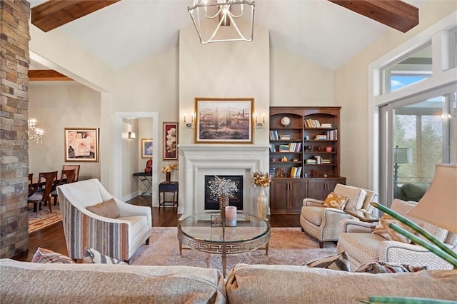 living area featuring a notable chandelier, high vaulted ceiling, a glass covered fireplace, wood finished floors, and beamed ceiling