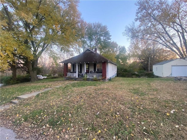 8733 E Saint John Ave, Kansas City, MO 64053 - bungalow featuring a front yard, a porch, and an outdoor structure