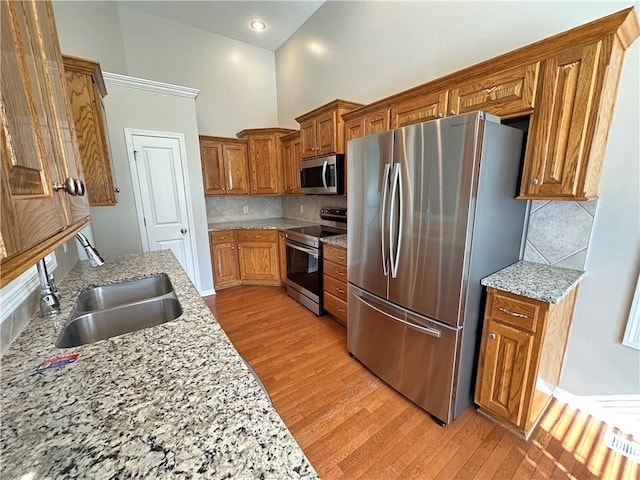 109 Deerfield Dr, Warrensburg, MO 64093 - kitchen featuring brown cabinetry, light wood-style floors, a sink, and appliances with stainless steel finishes