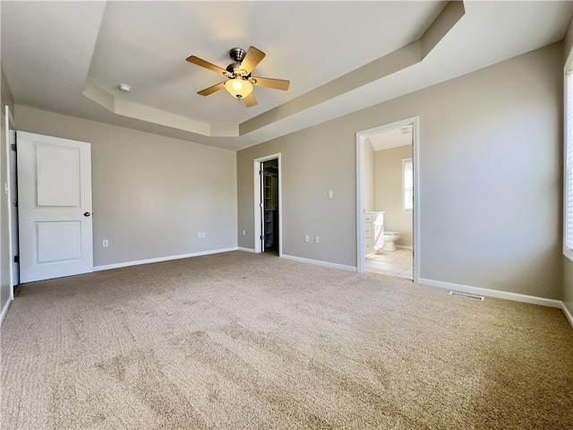 109 Deerfield Dr, Warrensburg, MO 64093 - unfurnished bedroom featuring ensuite bathroom, baseboards, a raised ceiling, carpet, and a walk in closet