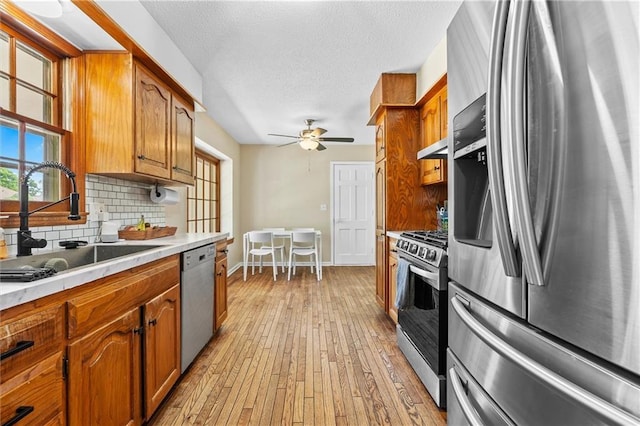kitchen featuring stainless steel appliances, a sink, light countertops, tasteful backsplash, and a textured ceiling