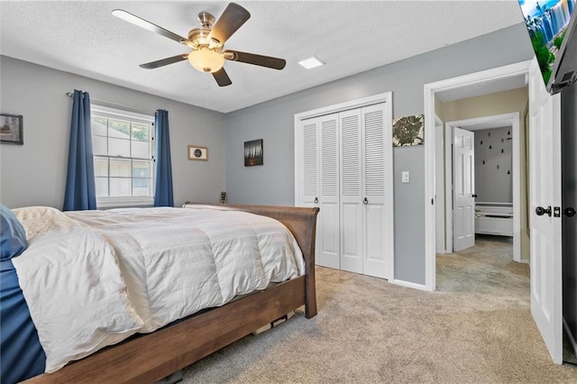 carpeted bedroom with a closet, a ceiling fan, and a textured ceiling