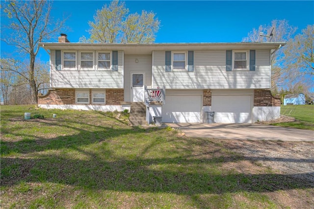 raised ranch with brick siding, an attached garage, a chimney, concrete driveway, and a front lawn