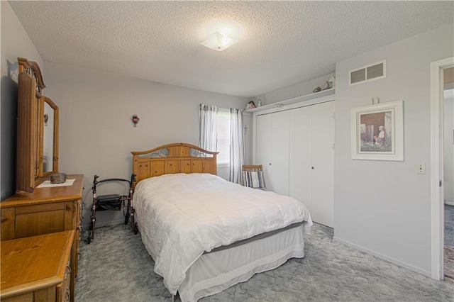 carpeted bedroom with a closet and a textured ceiling