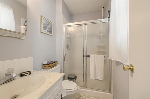 full bath featuring a shower stall, toilet, vanity, and a textured ceiling