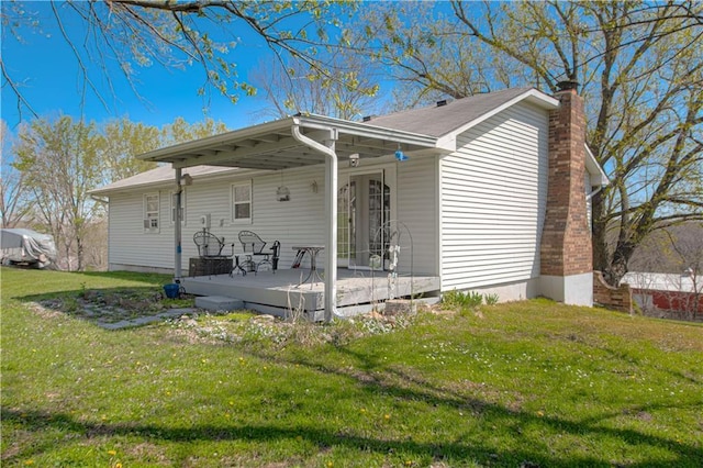 rear view of property featuring a yard, a chimney, and a deck