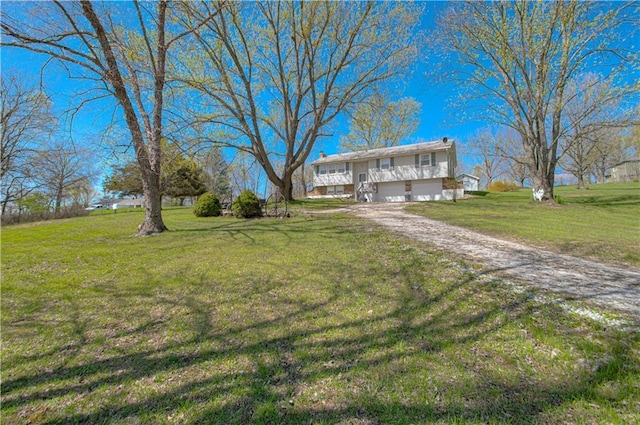 split foyer home with an attached garage, a front yard, and dirt driveway