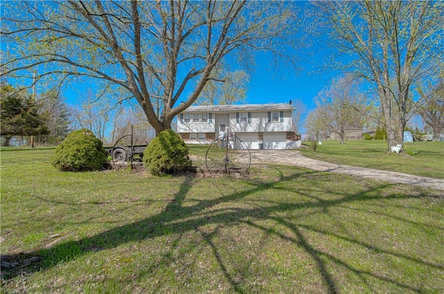rear view of house featuring driveway, an attached garage, and a lawn