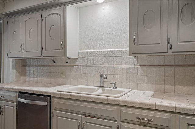 12500 Overbrook Rd, Leawood, KS 66209 - kitchen featuring stainless steel dishwasher, a sink, wallpapered walls, gray cabinets, and tile counters
