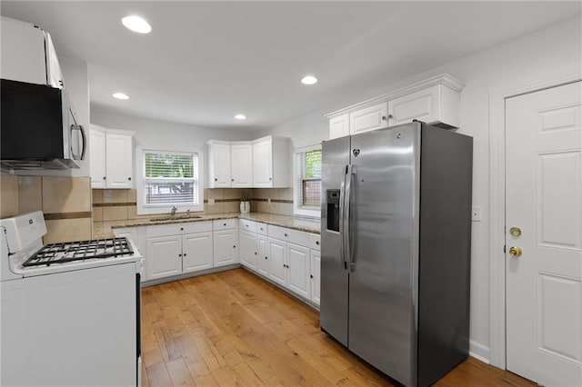 805 N 18th St, Kansas City, KS 66102 - kitchen with appliances with stainless steel finishes, light wood-style flooring, backsplash, white cabinetry, and recessed lighting