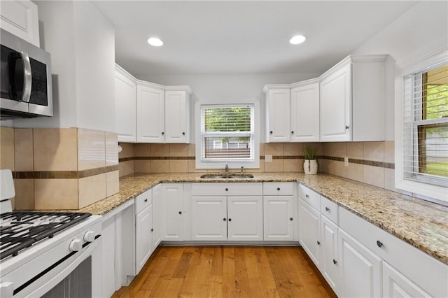 805 N 18th St, Kansas City, KS 66102 - kitchen featuring gas range gas stove, stainless steel microwave, a sink, light wood finished floors, and white cabinetry