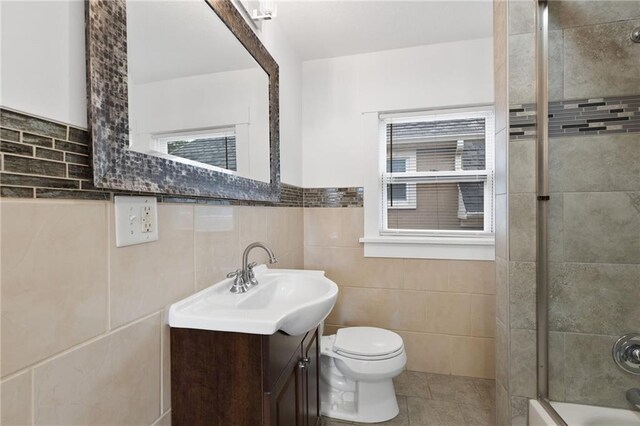 805 N 18th St, Kansas City, KS 66102 - bathroom with tile patterned floors, tile walls, toilet, vanity, and shower / bath combination with glass door