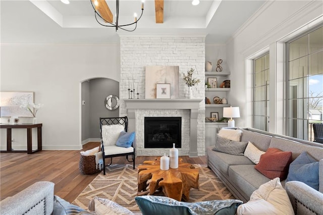8016 Round Prairie St, Shawnee, KS 66220 - living area with wood finished floors, arched walkways, a large fireplace, a raised ceiling, and a notable chandelier