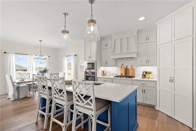 8016 Round Prairie St, Shawnee, KS 66220 - kitchen featuring stainless steel appliances, light countertops, white cabinetry, wall chimney exhaust hood, and a center island with sink