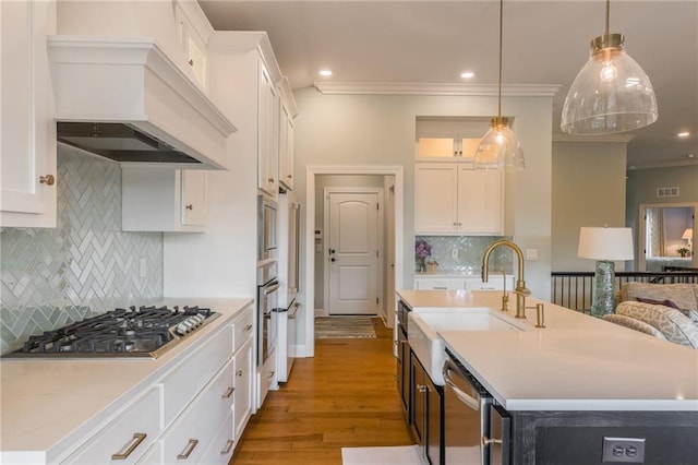 420 NW Kaylea Ct, Lees Summit, MO 64081 - kitchen with appliances with stainless steel finishes, ornamental molding, custom exhaust hood, white cabinetry, and tasteful backsplash