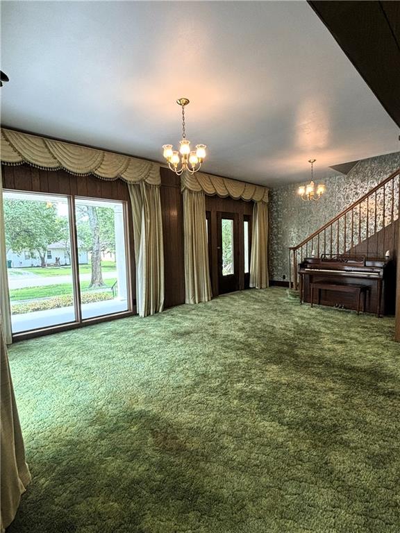 214 W 5th St, Lebo, KS 66856 - unfurnished living room featuring a chandelier, carpet floors, wallpapered walls, and stairway