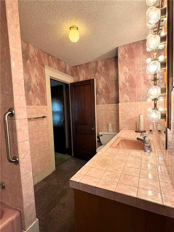 214 W 5th St, Lebo, KS 66856 - full bath with tile walls, a textured ceiling, vanity, and tub / shower combination