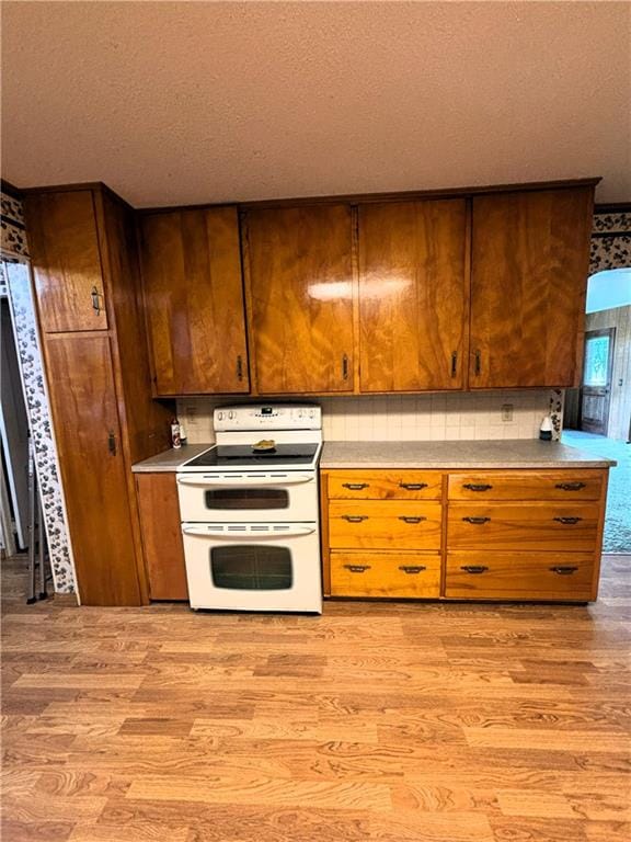 214 W 5th St, Lebo, KS 66856 - kitchen with range with two ovens, light wood-style floors, a textured ceiling, light countertops, and brown cabinets