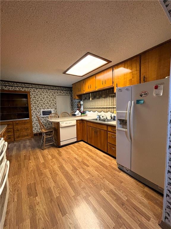 214 W 5th St, Lebo, KS 66856 - kitchen featuring brown cabinetry, a textured ceiling, fridge with ice dispenser, wallpapered walls, and light wood-style floors
