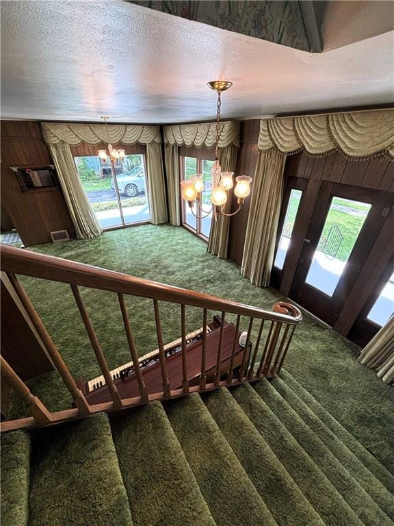214 W 5th St, Lebo, KS 66856 - staircase with a chandelier, carpet floors, a textured ceiling, and wood walls