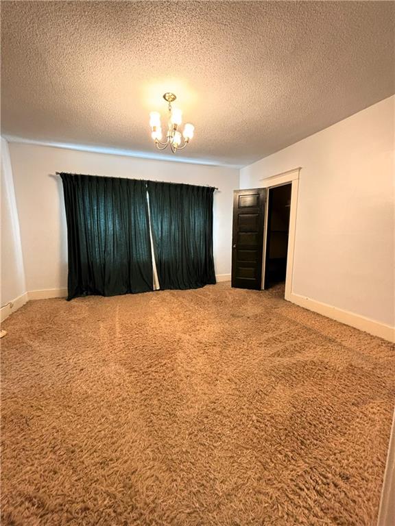 214 W 5th St, Lebo, KS 66856 - carpeted empty room featuring a chandelier and a textured ceiling