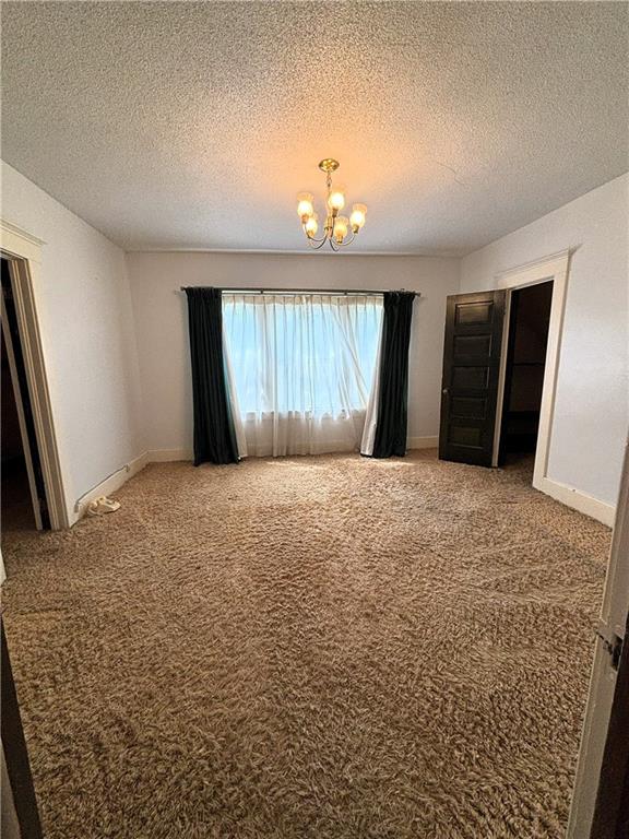 214 W 5th St, Lebo, KS 66856 - spare room featuring a chandelier, carpet flooring, and a textured ceiling