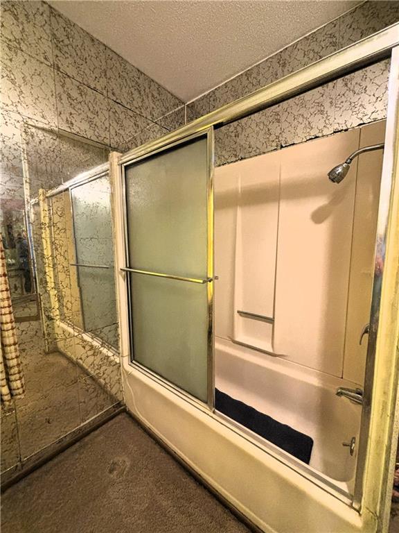 214 W 5th St, Lebo, KS 66856 - bathroom with combined bath / shower with glass door and a textured ceiling