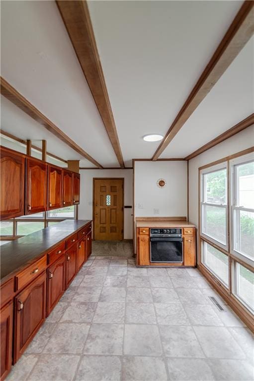717 Y St, Atchison, KS 66002 - kitchen with oven, brown cabinetry, beamed ceiling, dark countertops, and light stone finish floors