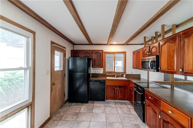 717 Y St, Atchison, KS 66002 - kitchen featuring black appliances, dark countertops, beamed ceiling, stone finish flooring, and brown cabinets