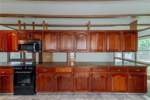 717 Y St, Atchison, KS 66002 - kitchen featuring stainless steel microwave, black / electric stove, dark countertops, and brown cabinetry