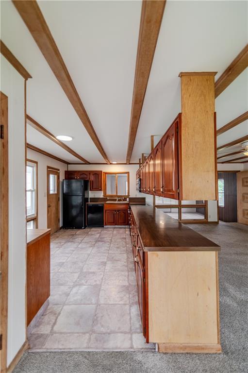 717 Y St, Atchison, KS 66002 - kitchen featuring black appliances, beam ceiling, dark countertops, brown cabinetry, and light colored carpet