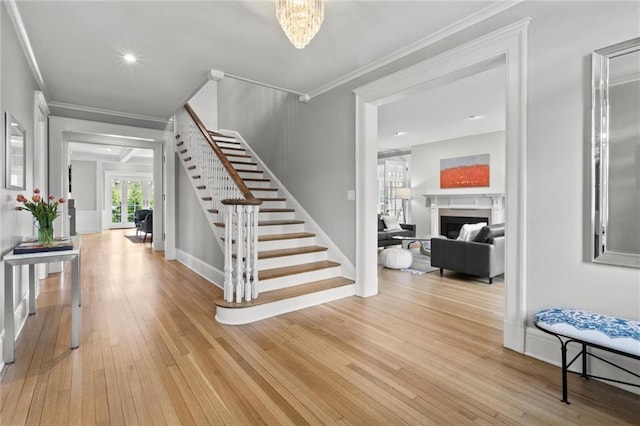 4525 Kenwood Ave, Kansas City, MO 64110 - entryway featuring baseboards, a fireplace, stairway, crown molding, and light wood finished floors