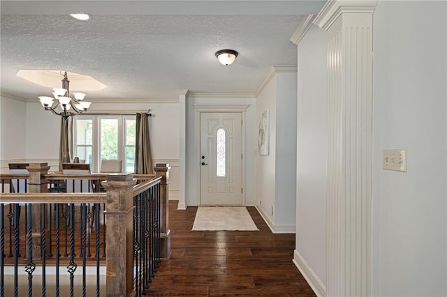 9015 Craig Dr, De Soto, KS 66018 - foyer entrance featuring a textured ceiling, dark wood-type flooring, a chandelier, ornamental molding, and baseboards