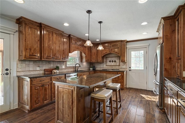9015 Craig Dr, De Soto, KS 66018 - kitchen with appliances with stainless steel finishes, brown cabinetry, healthy amount of natural light, dark wood finished floors, and crown molding