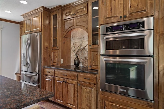 9015 Craig Dr, De Soto, KS 66018 - kitchen featuring stainless steel appliances, ornamental molding, recessed lighting, glass insert cabinets, and dark stone countertops