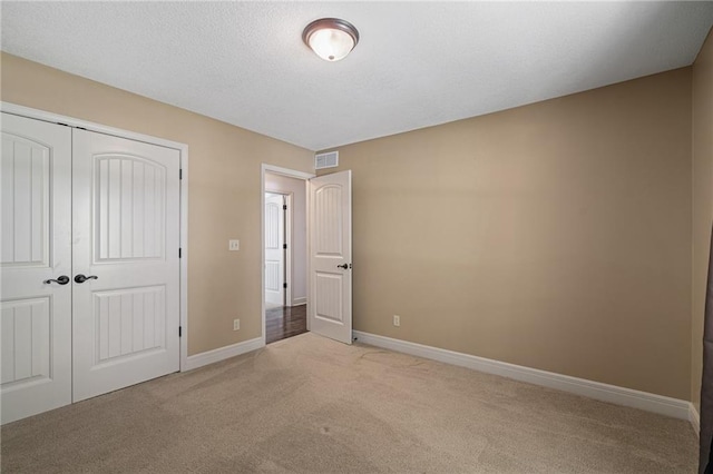 9015 Craig Dr, De Soto, KS 66018 - unfurnished bedroom with light colored carpet, a closet, baseboards, and a textured ceiling